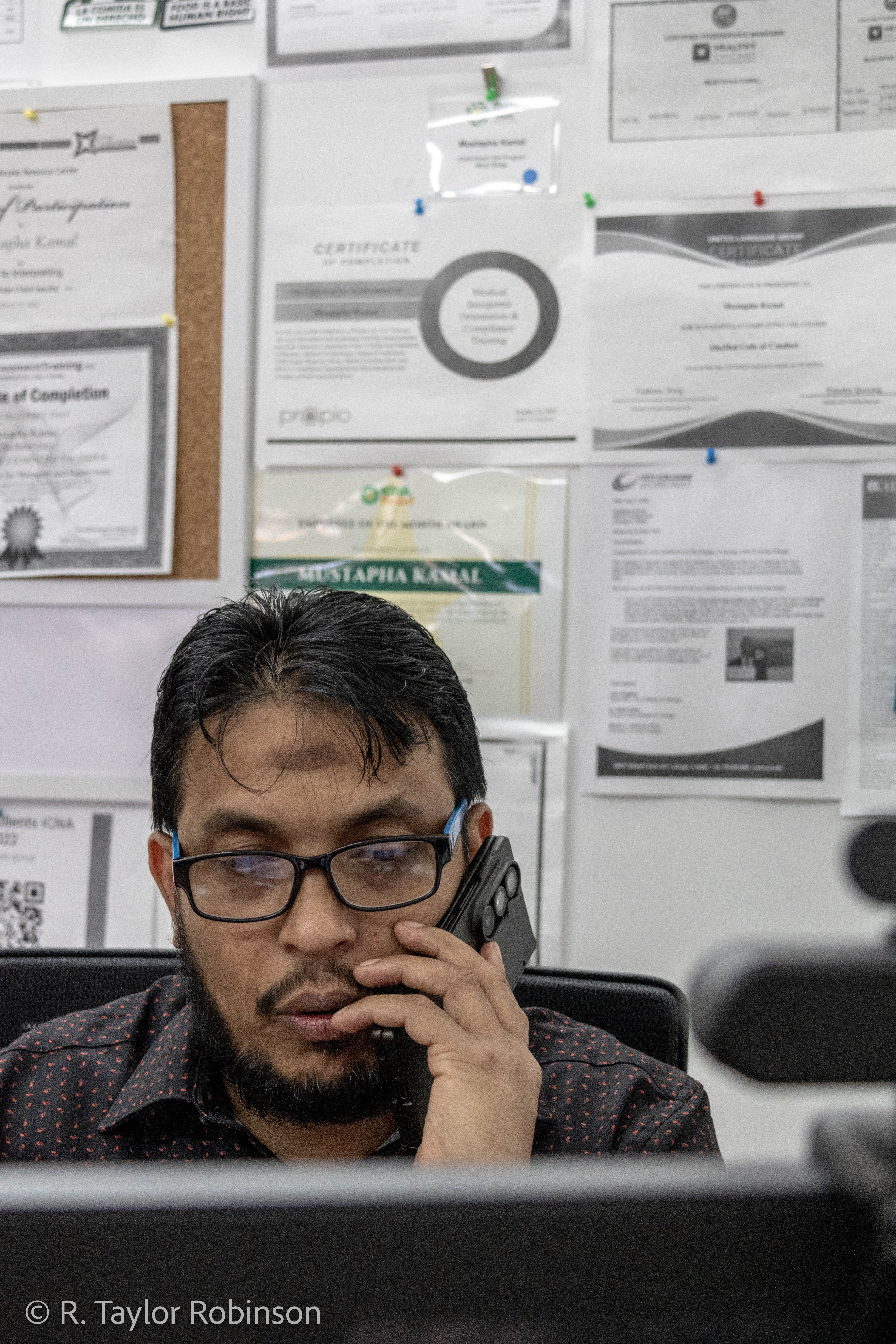 Mustapha Kamal talks on the phone at his desk at the Islamic Circle of North America, a non-profit and food pantry in Rogers Park that provides social services to refugees and immigrants. Kamal is a case worker and the director and only staff member of the resettlement agency for the Chicago chapter. "19 families have already settled in last three, four months," he said. He said he helps with "finding an apartment for them, helping them find any job, go to airport and pick them up, providing the food, connect to the resources, taking to the doctor office for refugees."
