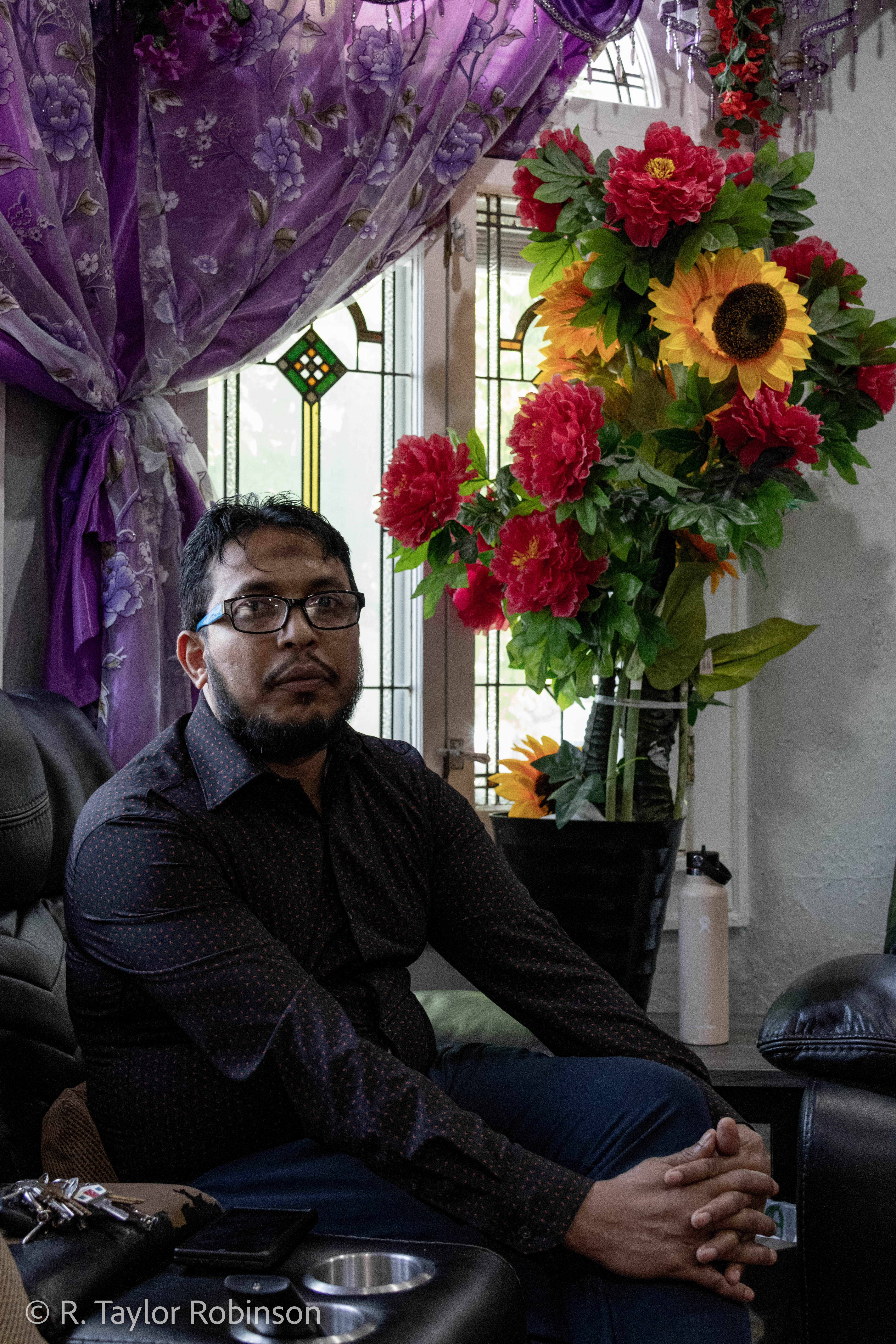 Kamal sits on his couch in front of the elaborate display of brightly colored flowers and purple curtains, decorations that, according to him, his wife brings home seemingly every time she goes out of the house. After two years in Bangladesh he decided he needed to leave and make money for his family so he got on a boat along with 90 other passengers headed illegally to Malaysia, where he had been promised higher wages by his friend. "Somehow the captain, he lost the way," he said. "And then we were floating in the sea for 27 days, and without food and water. Out of 91, almost 31 people dead."