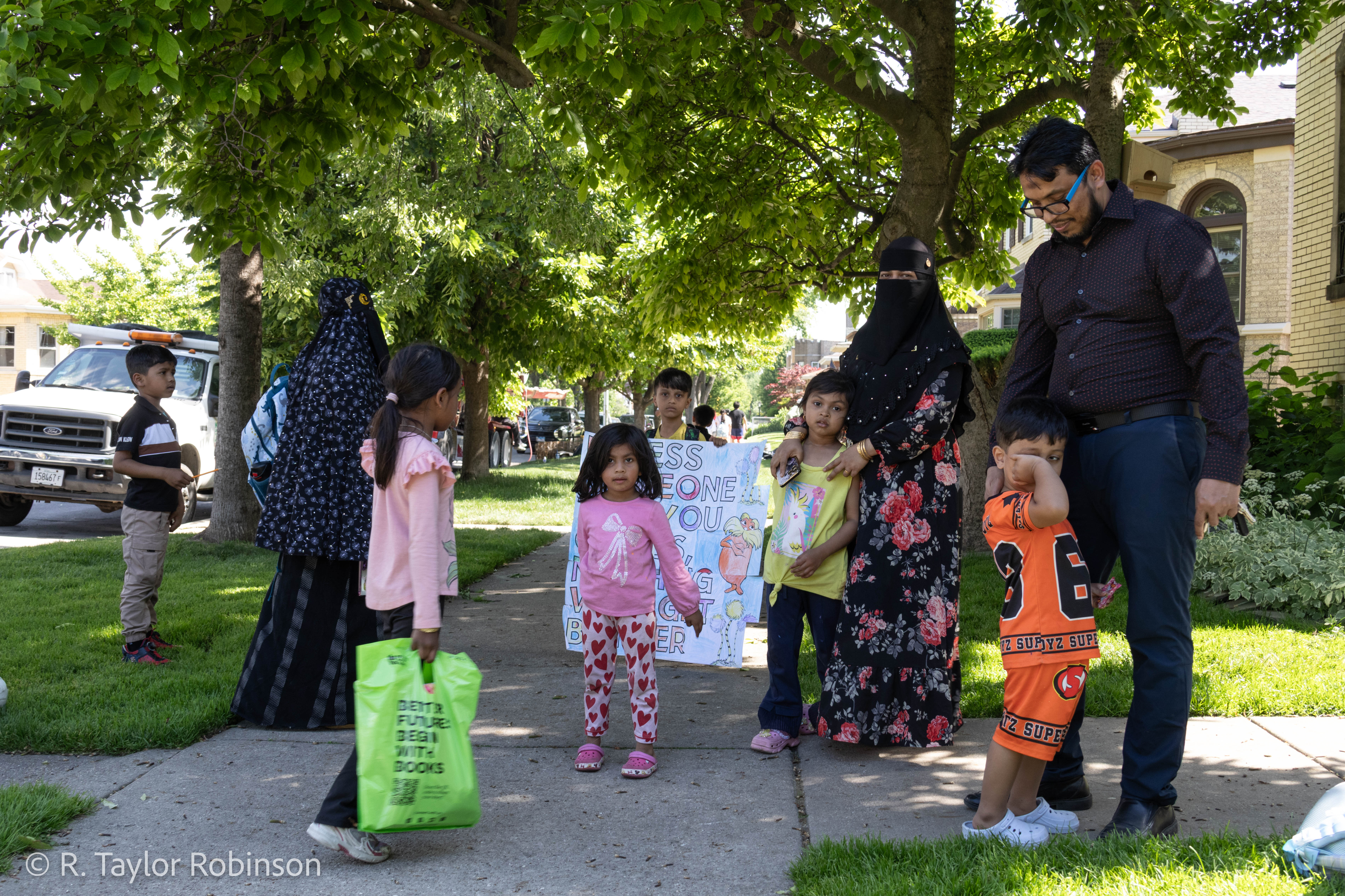 Kamal stands outside with his son Aziz, 3, shyly clutching his father’s leg, his wife Arafah stands behind him in a black hijab, her arms resting on the shoulders of their youngest daughter Jasmin, 5. In a deluge, dozens of children and mothers wearing hijab have materialized on the street outside of the school across from Kamal’s house.
