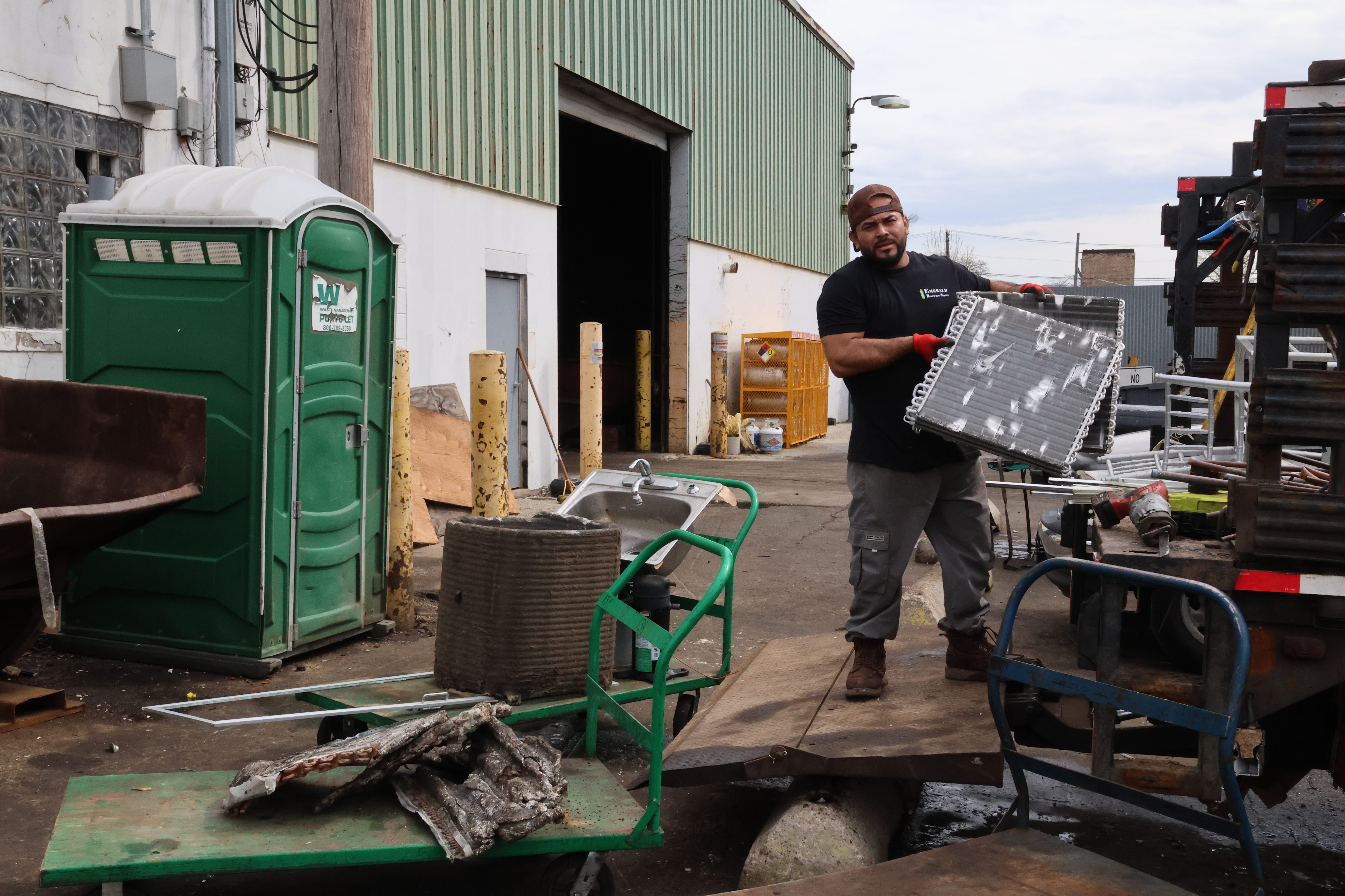Ulises Juarez, 36, a customer at Windy City Iron & Metal, holds up two radiators to show the camera. When asked what he likes to do, he said he likes having dinner with his family.