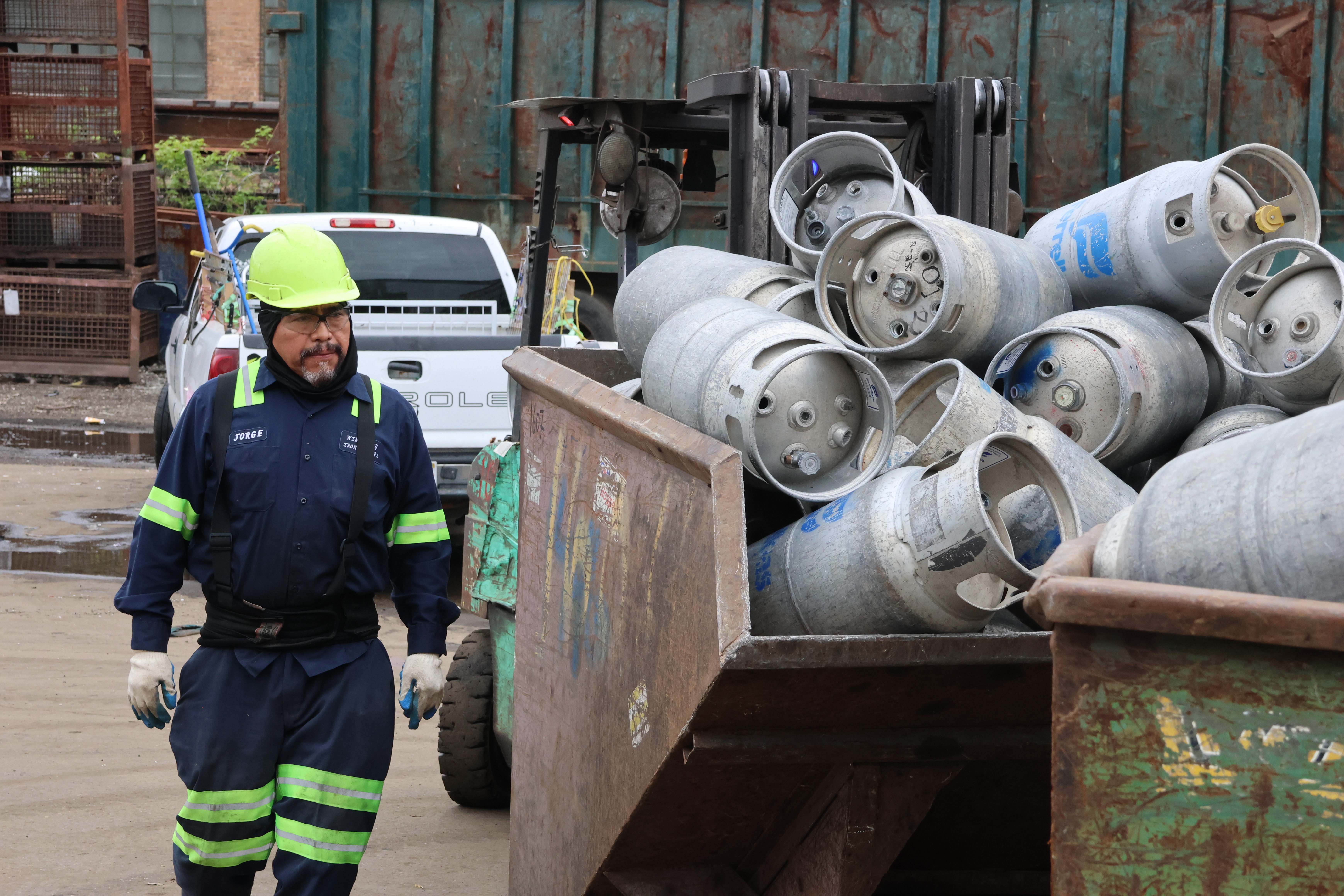 A forklift operator eyes the load of canisters he’s going to have to wheal into the back. Two customers of Windy City Iron & Metal are loading the bins with more canisters from a truck just out of frame.