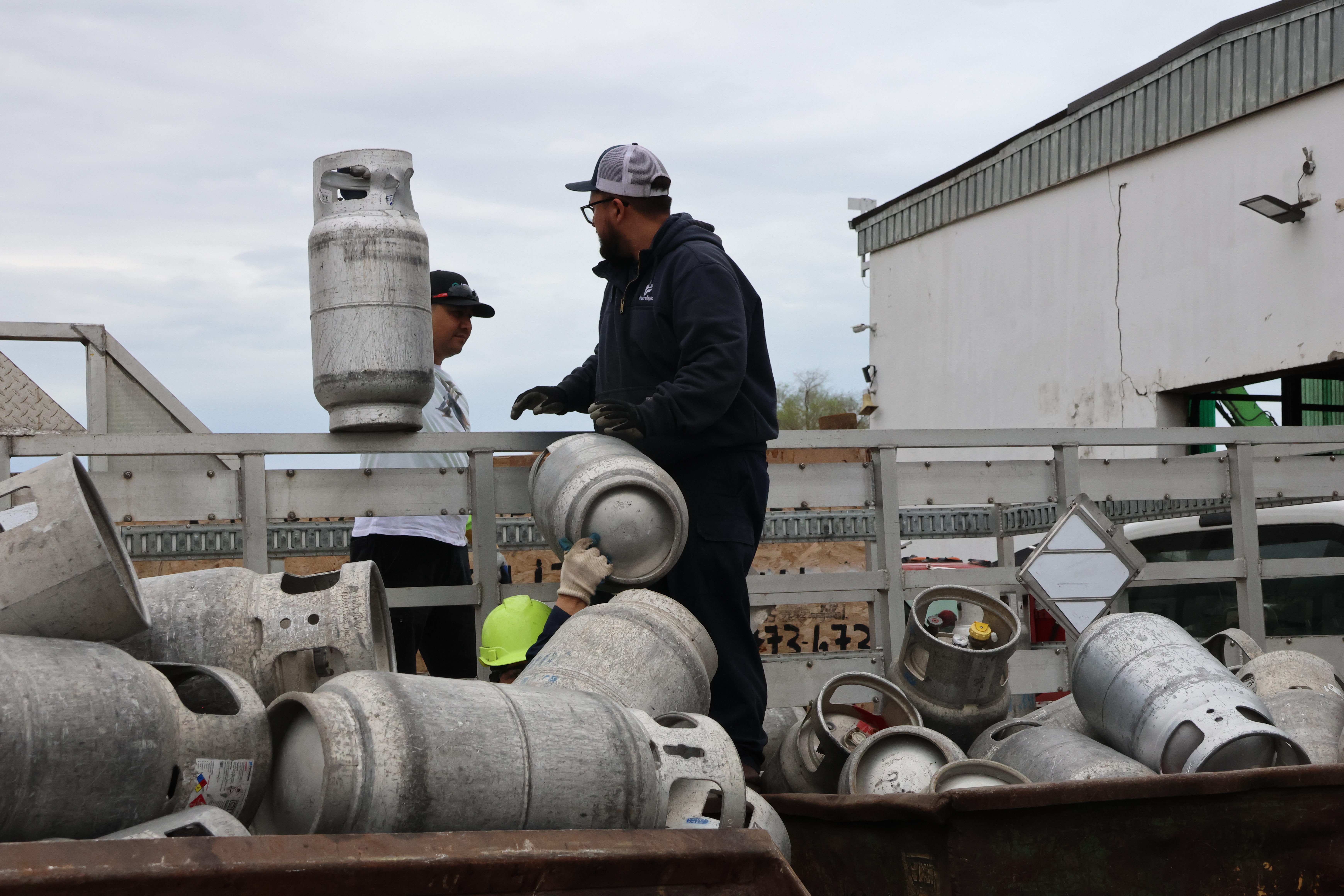 The two customers finish emptying their truck. They hand the last two canisters to the forklift operator.